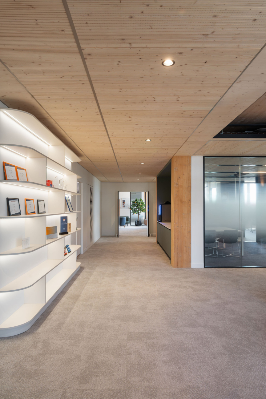 Couloir épuré aux lignes modernes et jeux de lumière, reliant les espaces de travail chez DKV