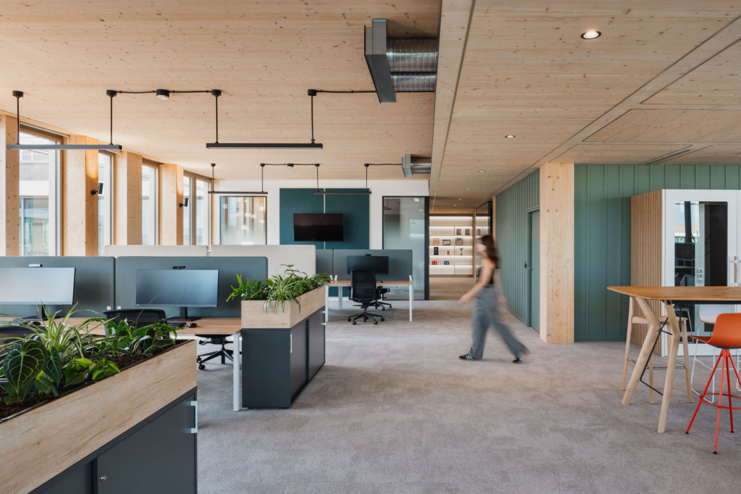 Open space DKV réalisé par ARCH.DESIGN, aménagement en bois clair, espaces verts et postes de travail ergonomiques.