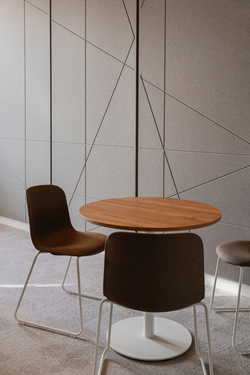 Salle de réunion DKV par ARCH.DESIGN, table ronde en bois et chaises modernes dans un décor minimaliste.