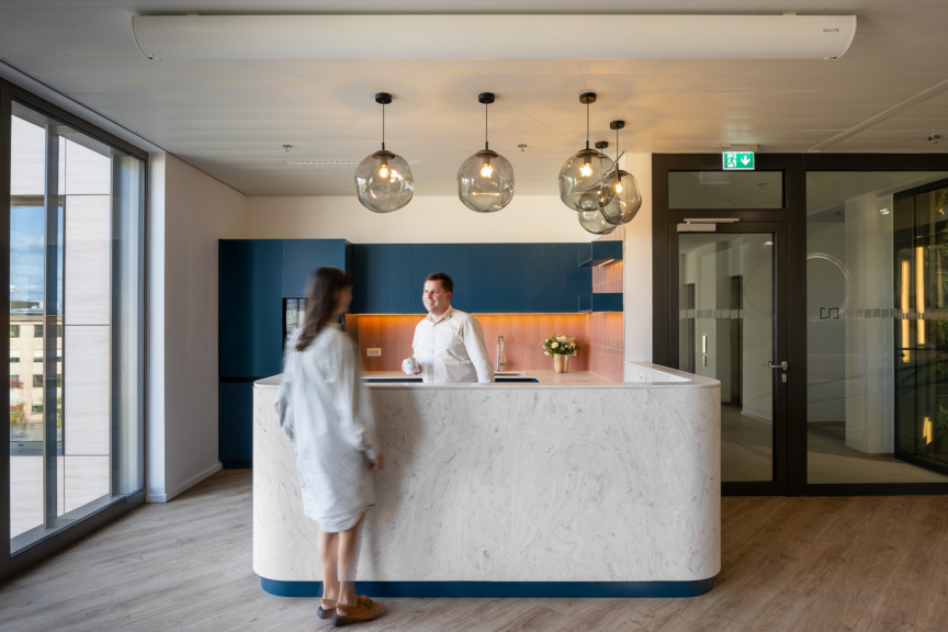 Espace d’accueil avec comptoir en marbre et luminaires suspendus, favorisant convivialité et échanges entre collaborateurs
