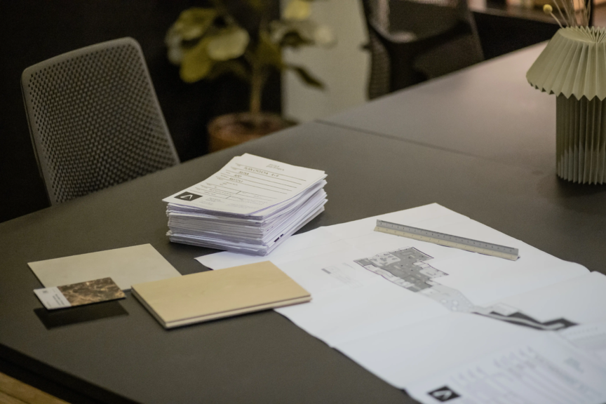 Dossier et plans d’architecture sur une table de travail.